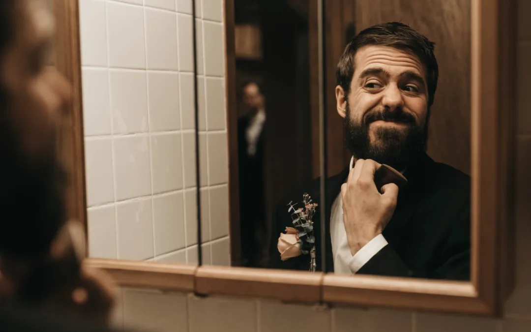 Groom getting ready in the mirror.