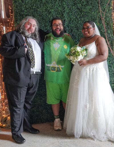 Bride and groom standing with their comedian at the reception.