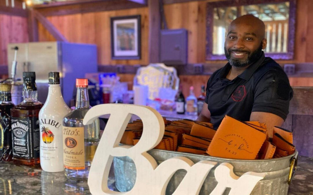 Bartender standing behind a bar with various liquor bottles and a decorative sign that says 'Bar'.