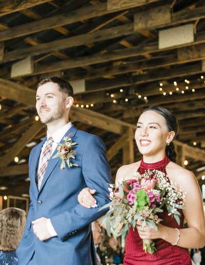 A man in a blue suit and a woman in a red dress walking together at a wedding reception.
